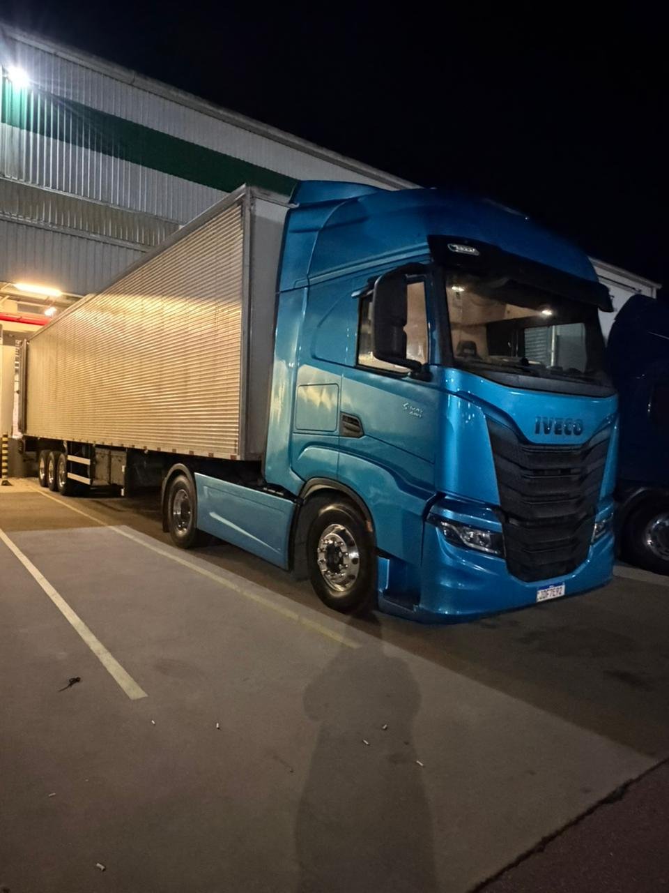 Caminhão Iveco S-Way da frota JHOW Transportes durante operação noturna